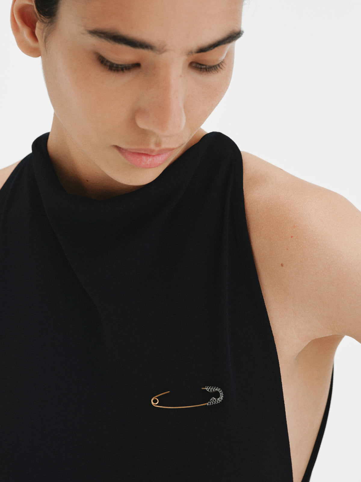 Charm bañado en oro amarillo con espinelas negras y forma de imperdible