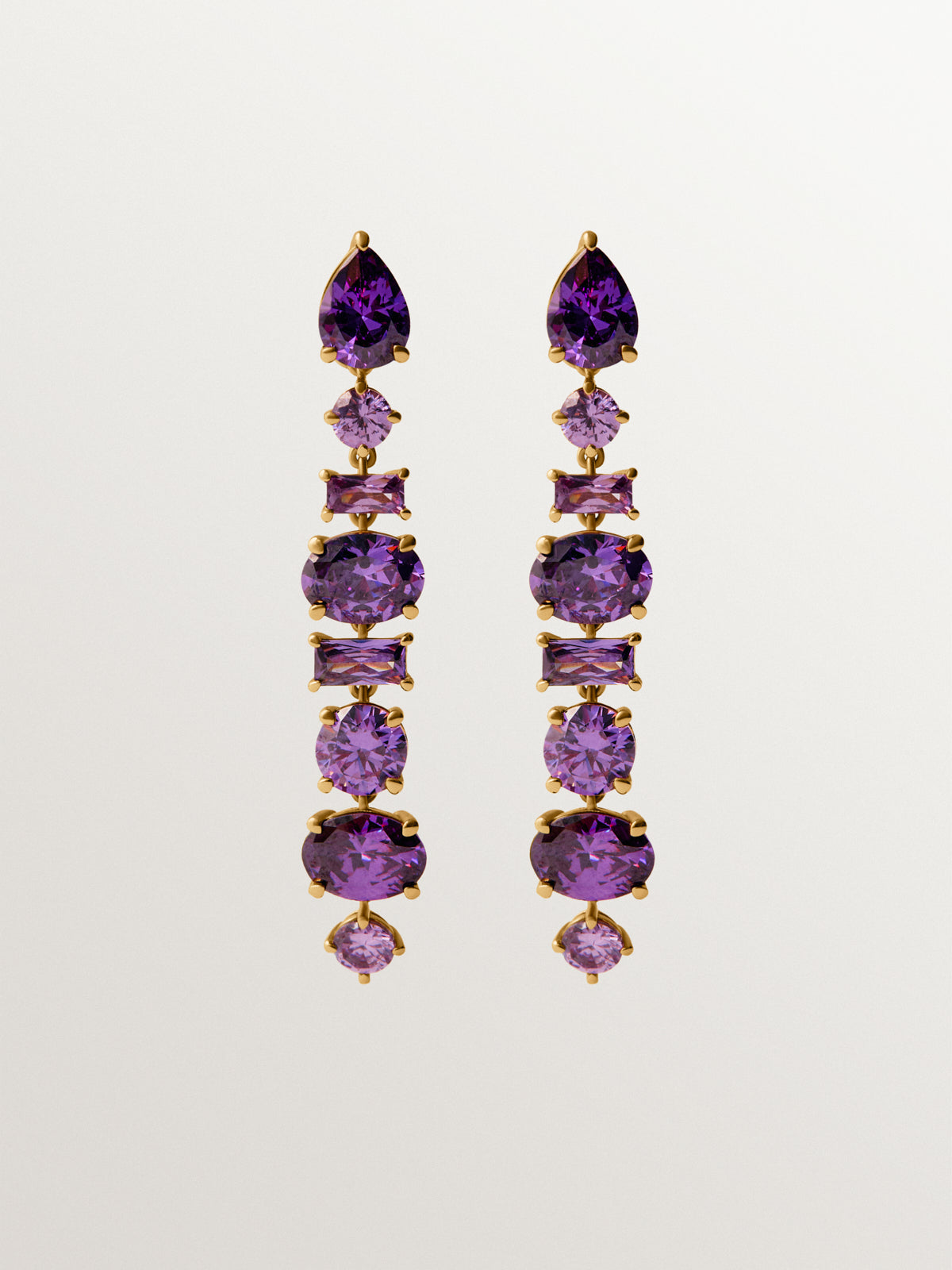 De longues boucles d’oreilles plaquées d’or jaune avec des cristaux violets