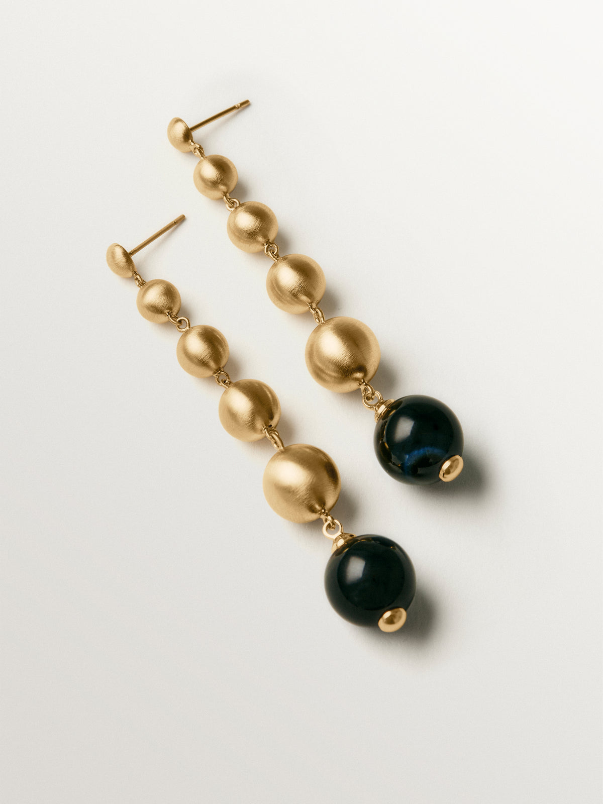 Pendientes largos bañados en oro amarillo con efecto cepillado, ágata negra y motivos de esferas