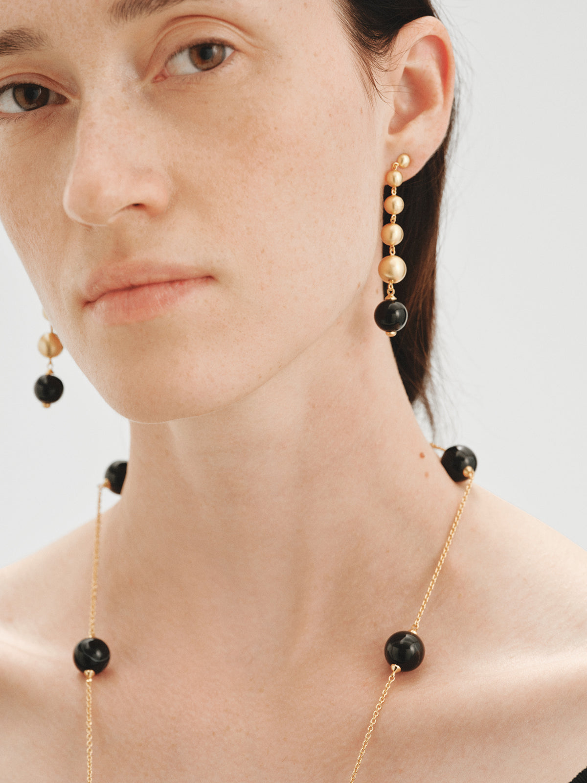 Pendientes largos bañados en oro amarillo con efecto cepillado, ágata negra y motivos de esferas