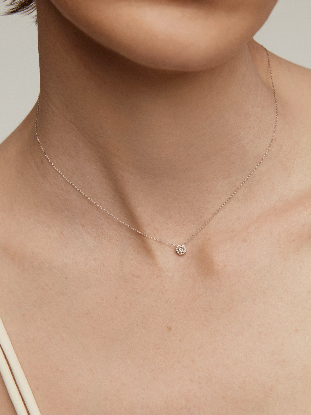 Colgante de oro blanco de 18K con diamante central de 0,05cts y orla de diamantes