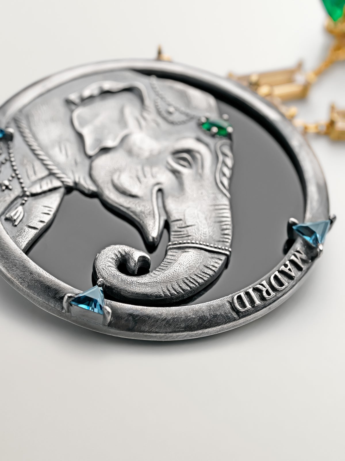 Broche de plata 925 y plata 925 bañada en oro amarillo de 18K con medalla de elefante y zafiros blancos, ónix verdes y topacios azul london
