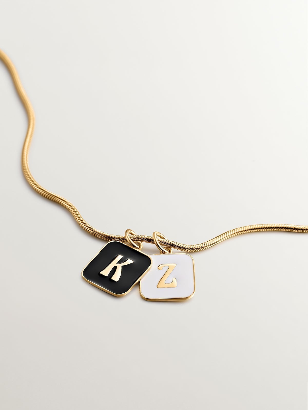 Charm de plata 925 bañada en oro amarillo de 18K con inicial K y esmalte negro con forma cuadrada
