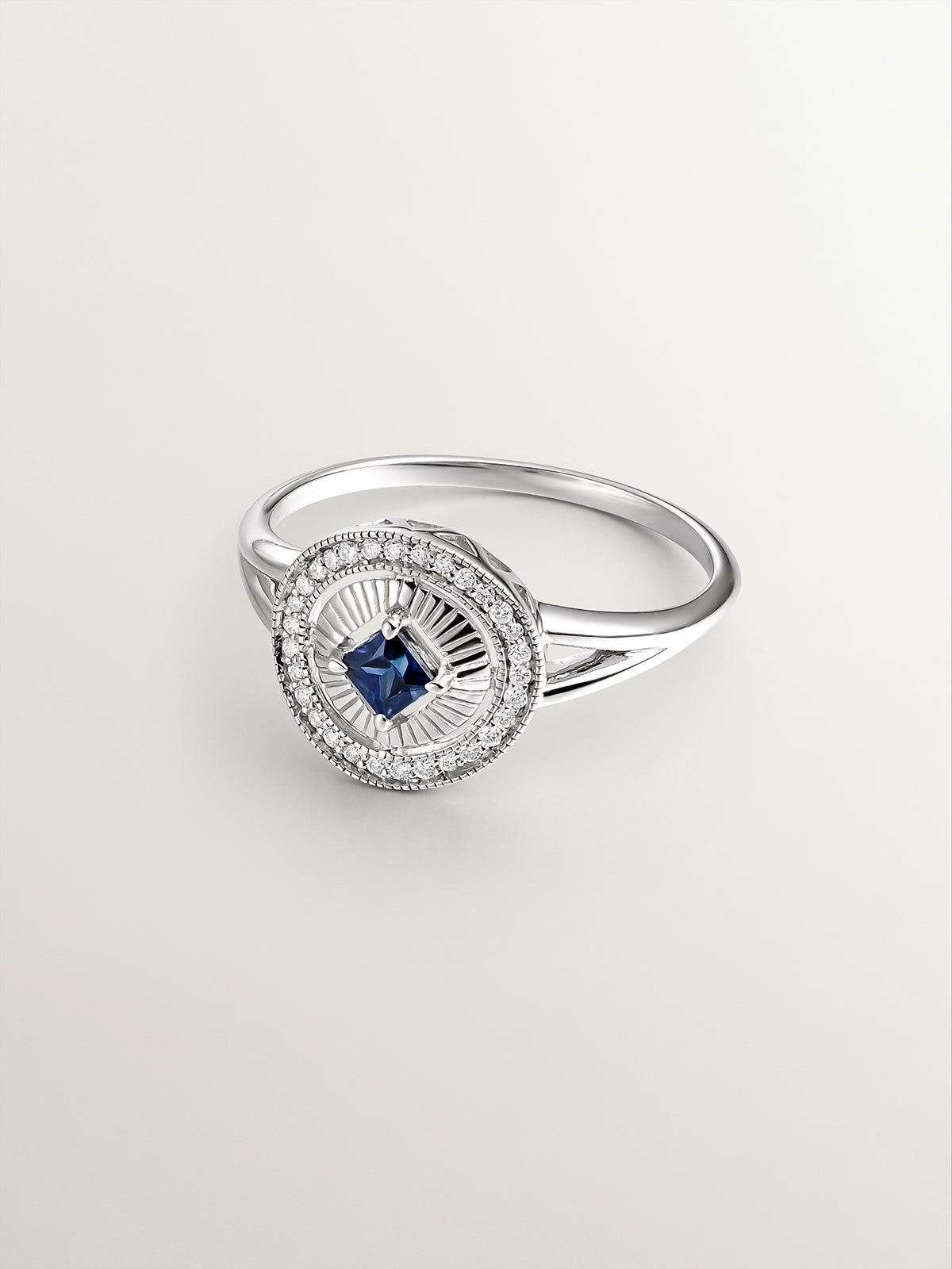 Anillo de oro blanco de 18K con diamantes en talla brillante y zafiro azul en talla princesa
