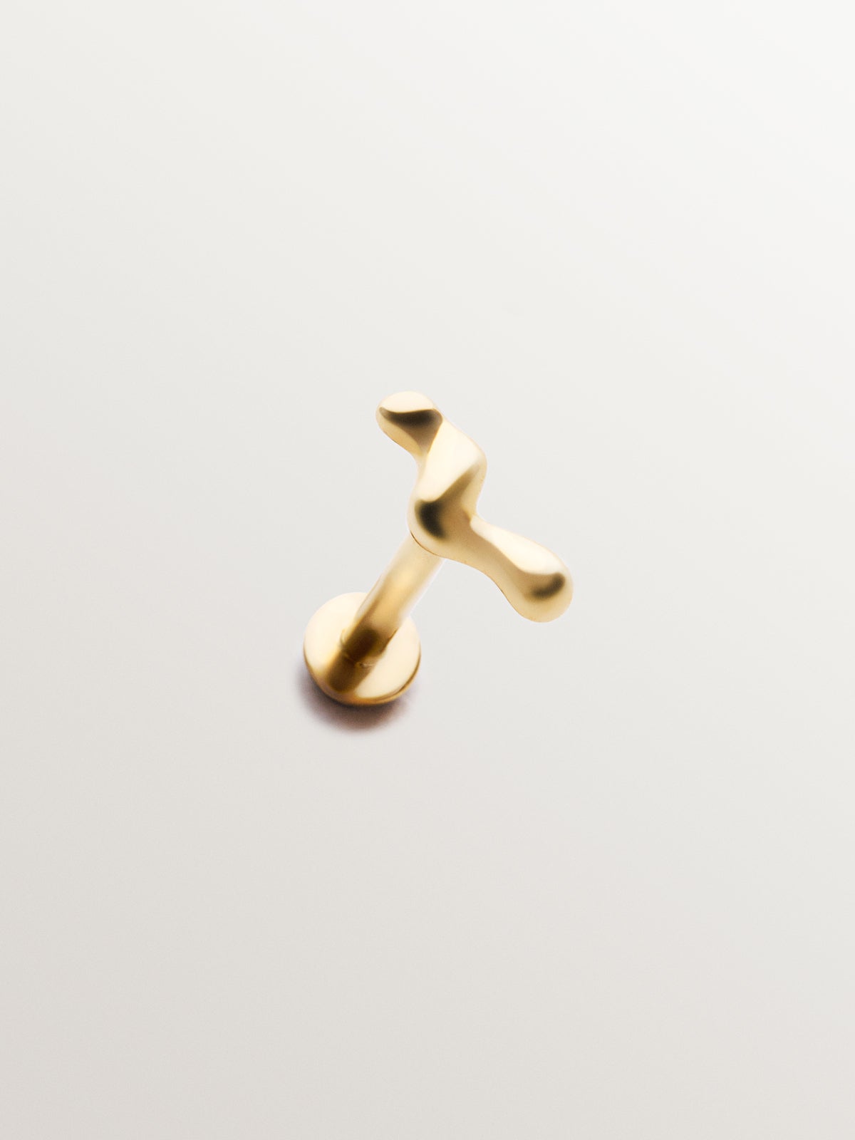 Piercing individual de oro amarillo de 18K con forma orgánica de ola.