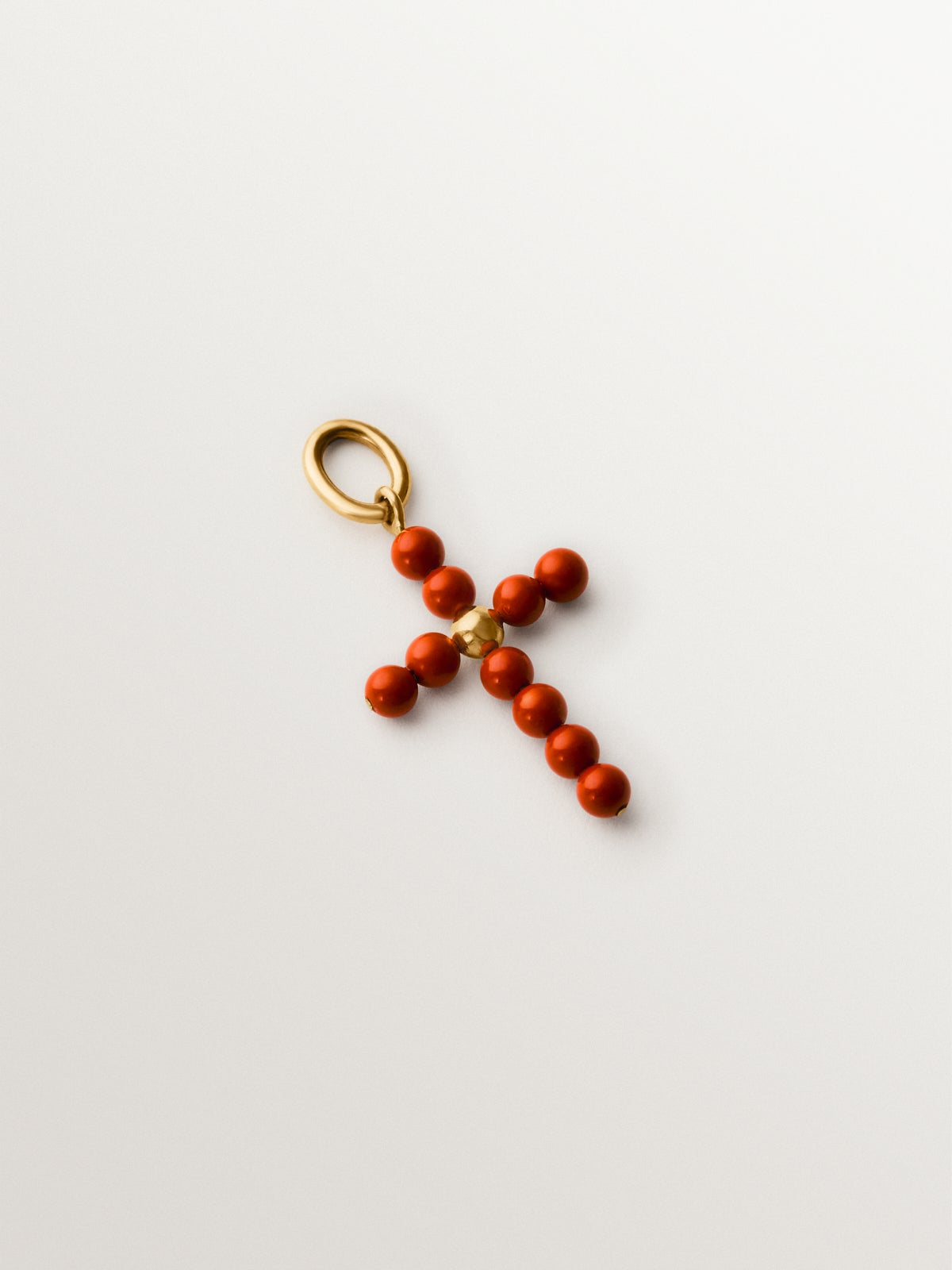 Charm de plata 925 bañada en oro amarillo de 18K con bolitas de coral y forma de cruz