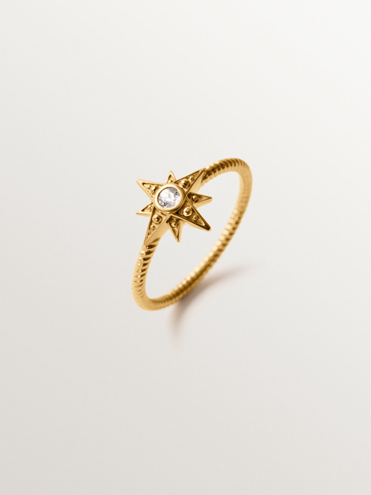 Anillo de plata 925 bañada en oro de 18K con estrella y topacio blanco en textura gallonada