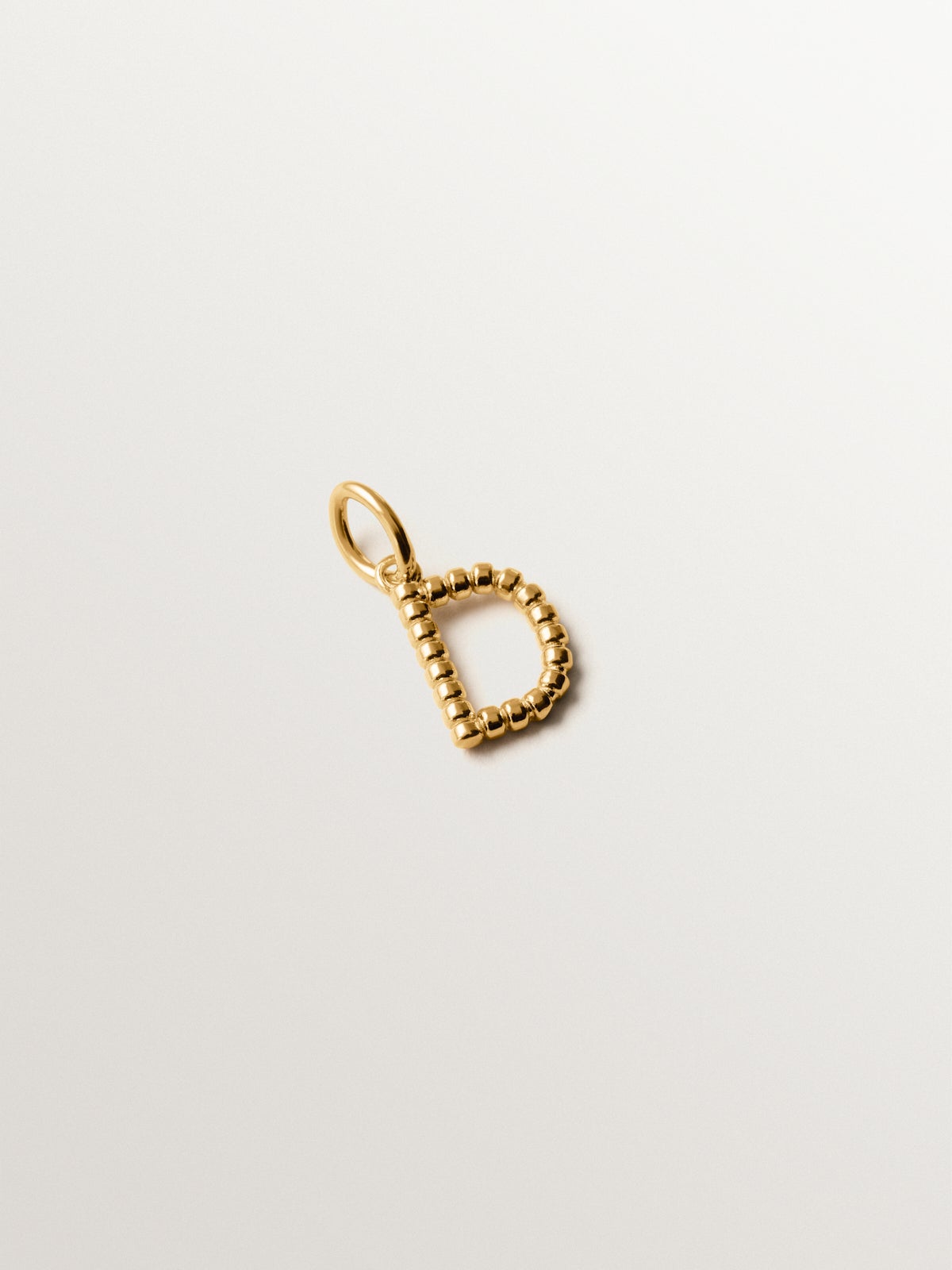 Charm de plata 925 bañada en oro amarillo de 18K con letra D y motivos de esferas