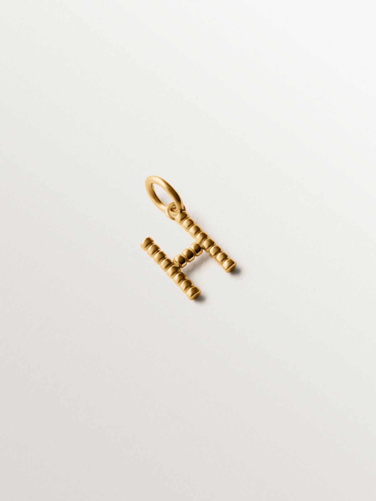 Charm de plata 925 bañada en oro amarillo de 18K con letra H y motivos de esferas