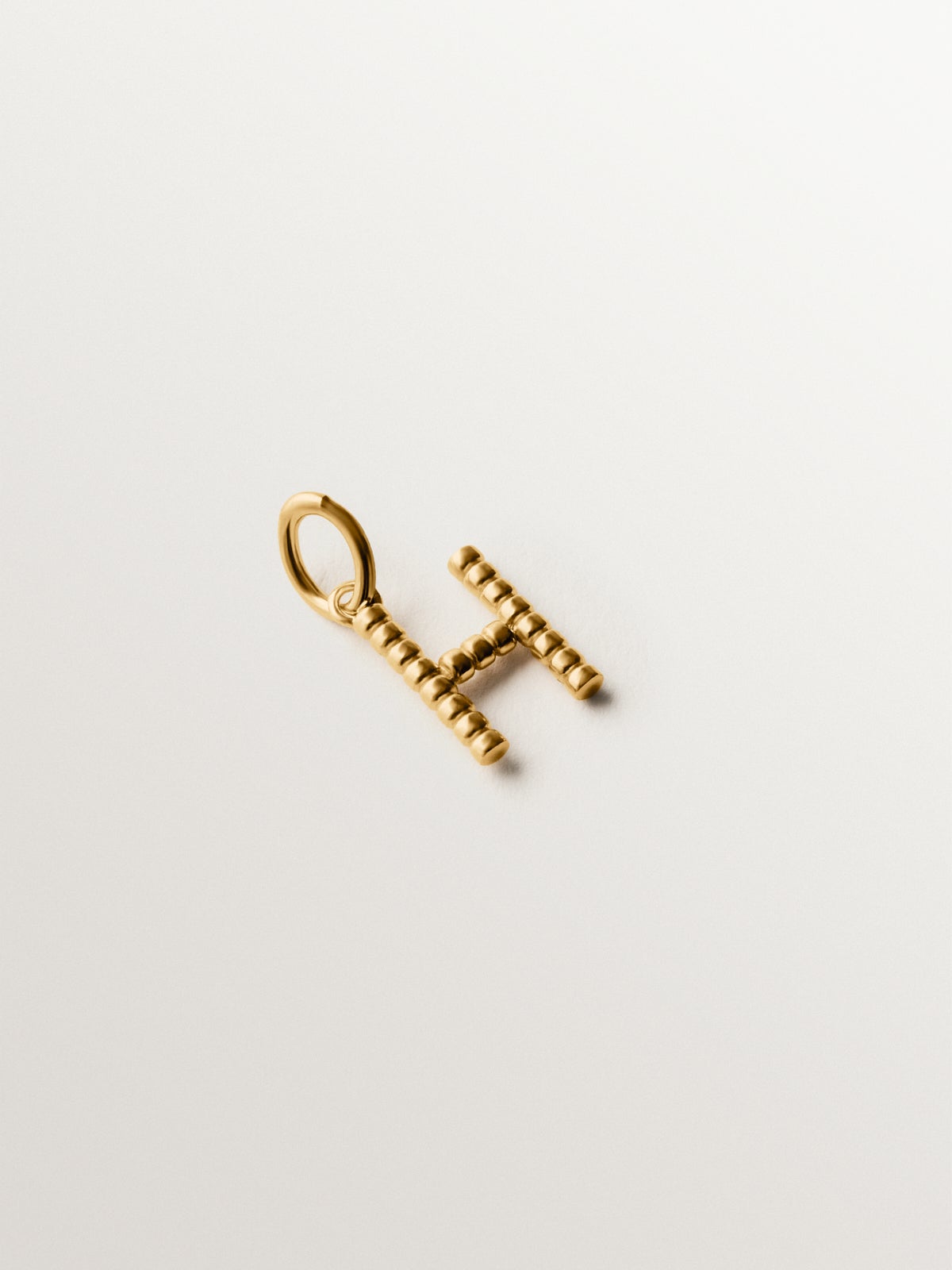 Charm de plata 925 bañada en oro amarillo de 18K con letra H y motivos de esferas