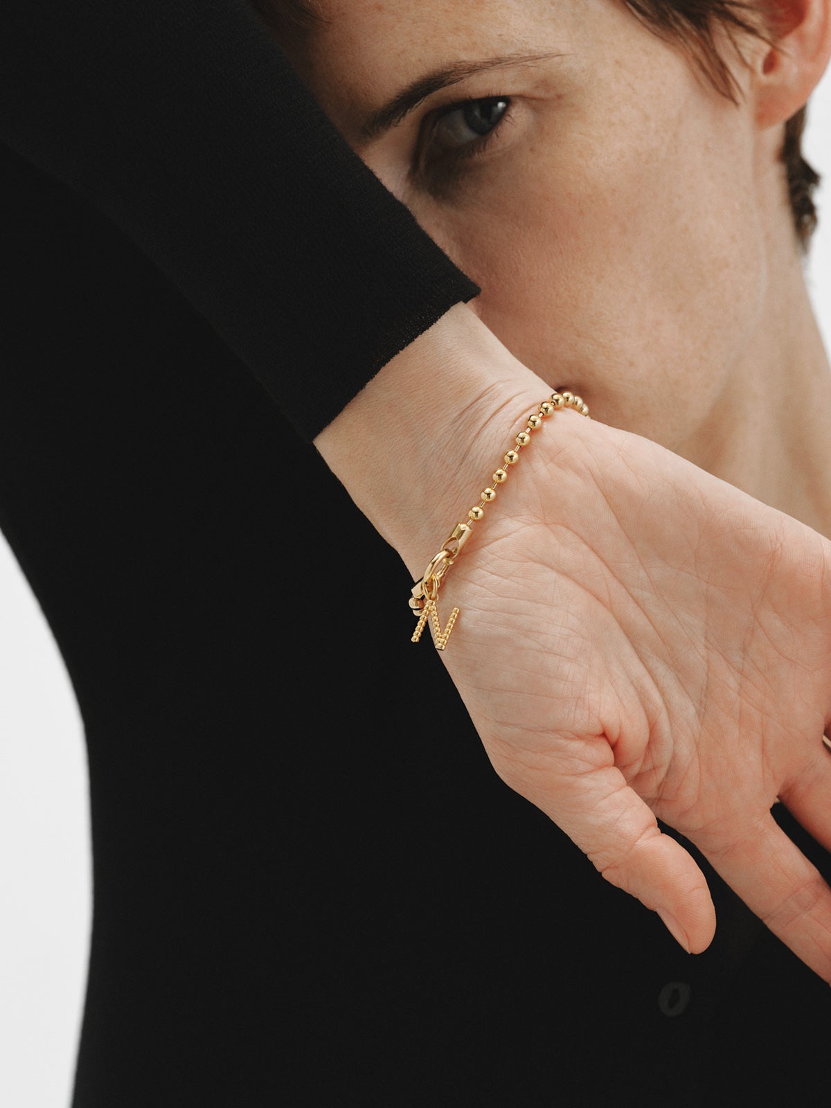 Charm de plata 925 bañada en oro amarillo de 18K con letra N y motivos de esferas