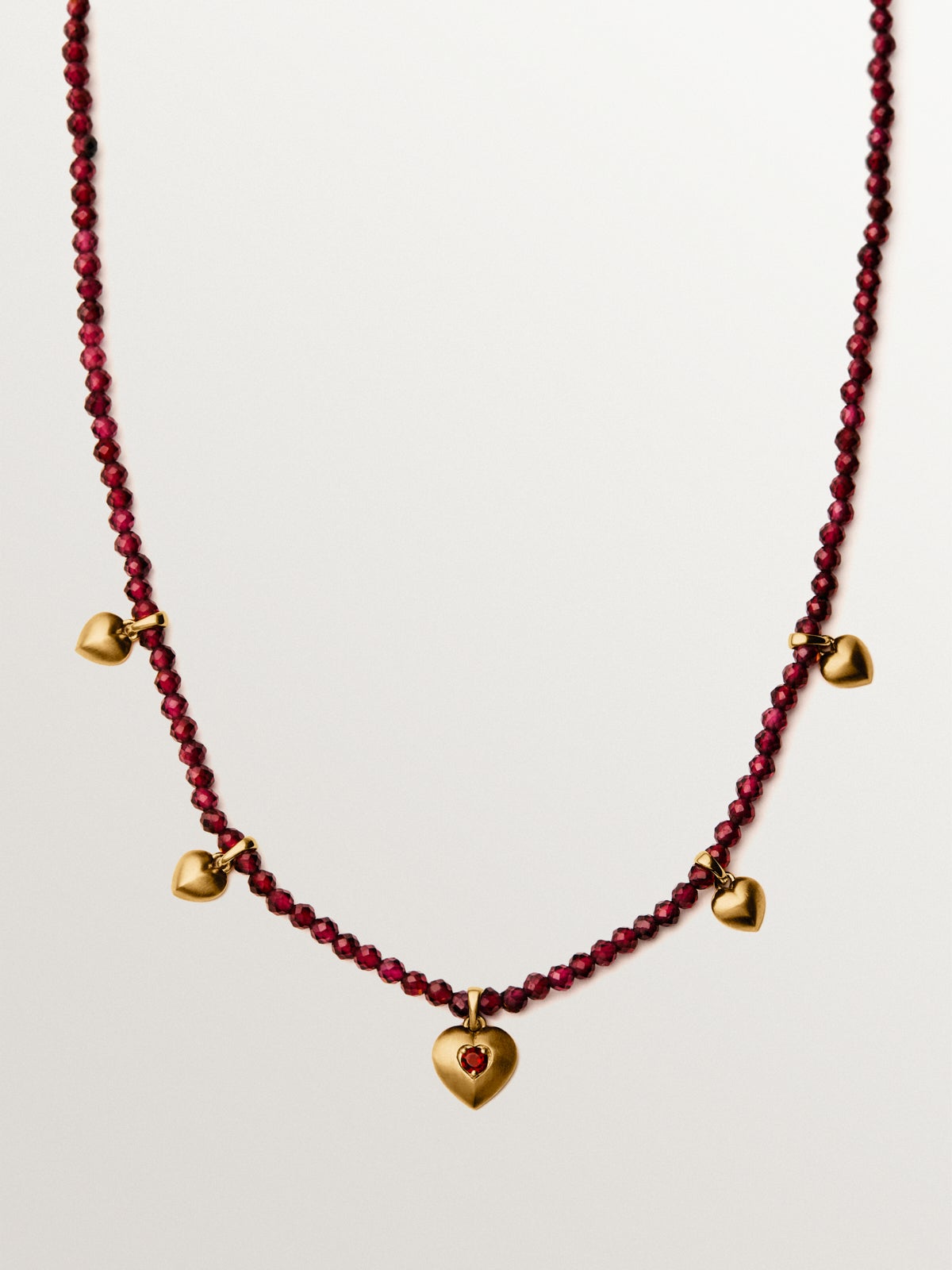 Collar de plata bañada en oro amarillo de 18K con cuentas de granates y motivos de corazón