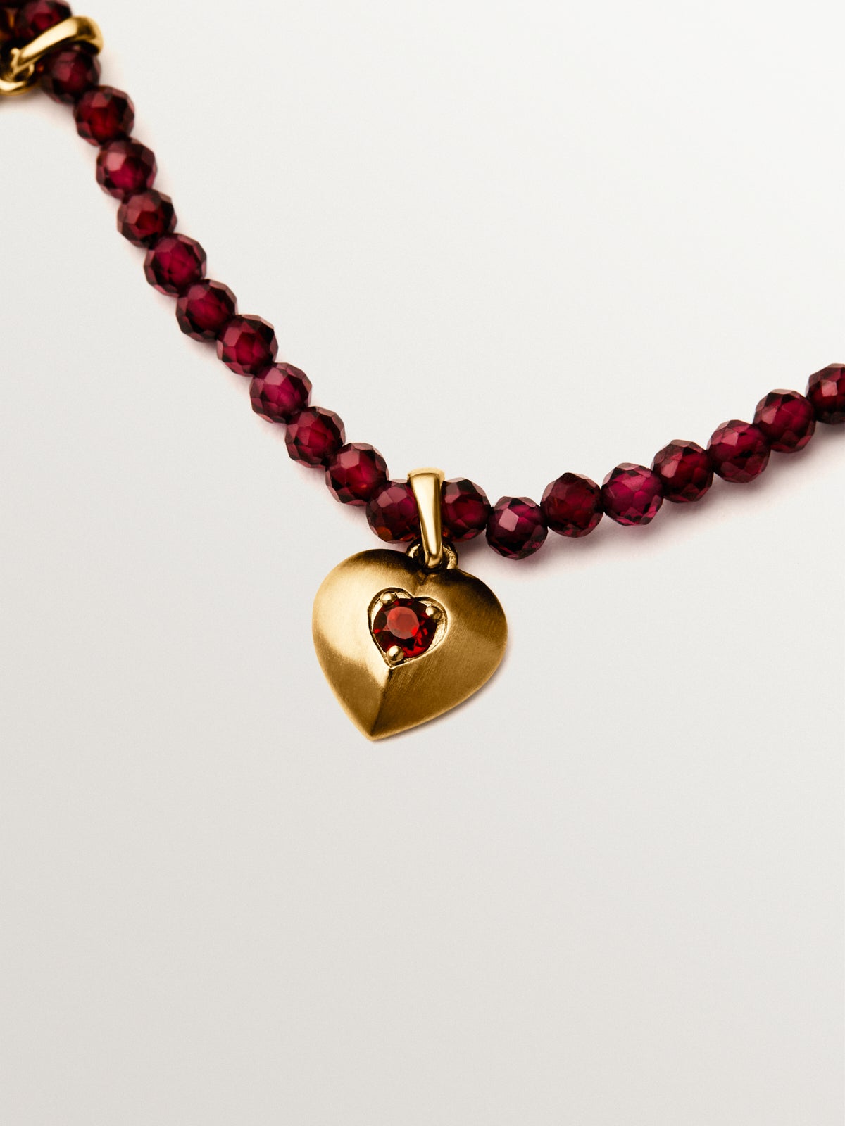 Collar de plata bañada en oro amarillo de 18K con cuentas de granates y motivos de corazón