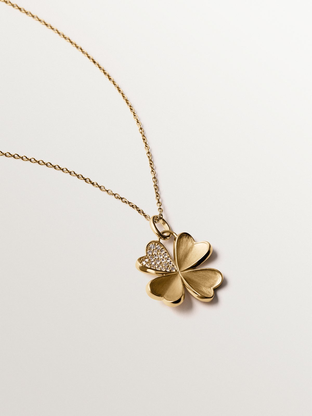 Charm de plata 925 bañada en oro amarillo de 18K con topacios blancos y forma de trébol