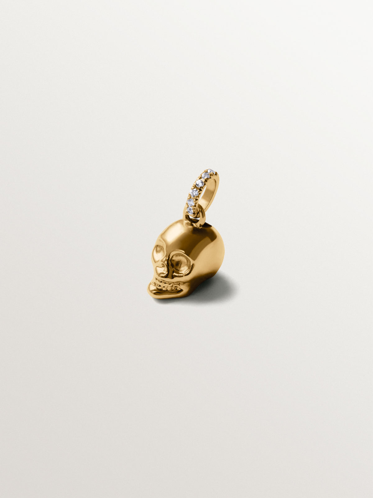 Charm de plata 925 bañado en oro amarillo de 18K con topacios blancos y forma de calavera