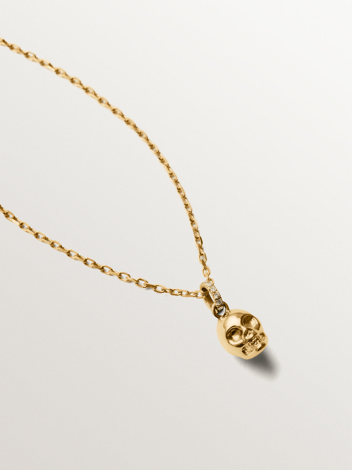 Charm de plata 925 bañado en oro amarillo de 18K con topacios blancos y forma de calavera