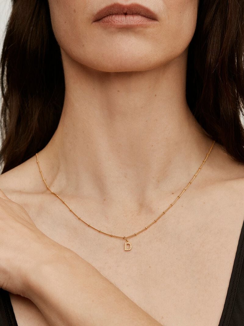 D initial charm made of 925 silver bathed in 18K yellow gold and white topaz. image number 1