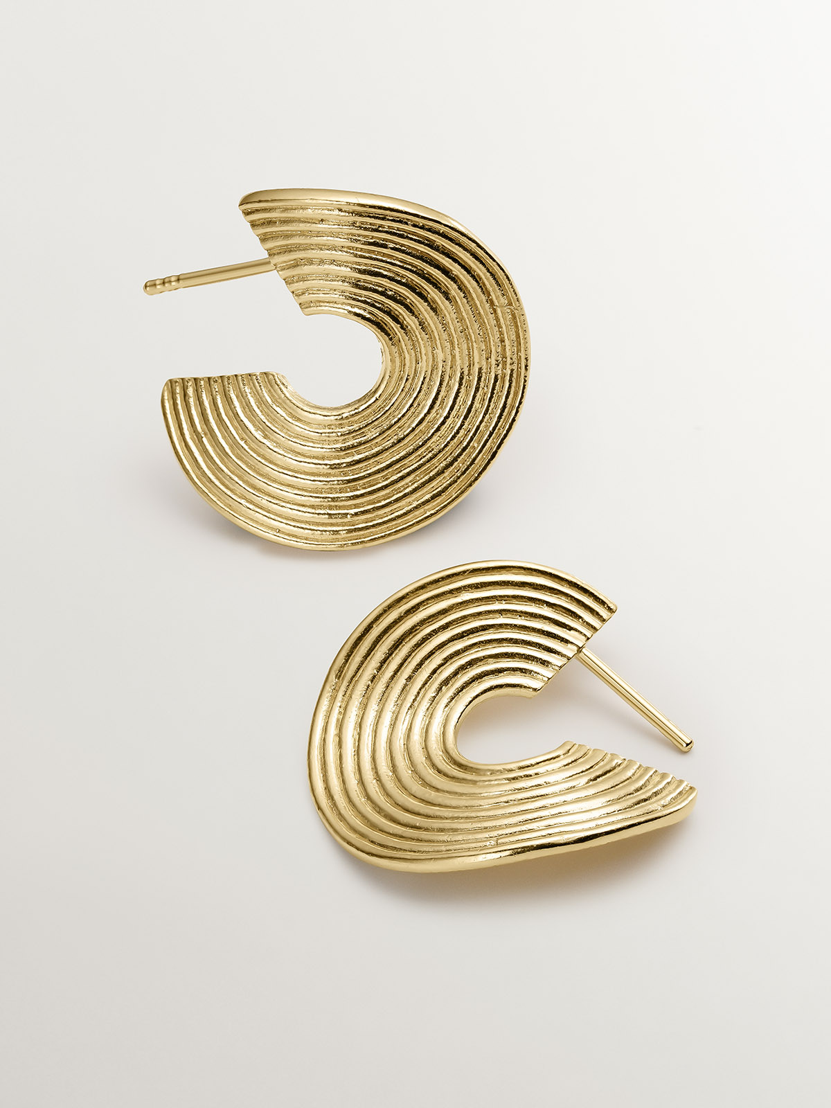 Medium sized hoop earrings made of 925 silver, bathed in 18K yellow gold with texture and irregular shape.