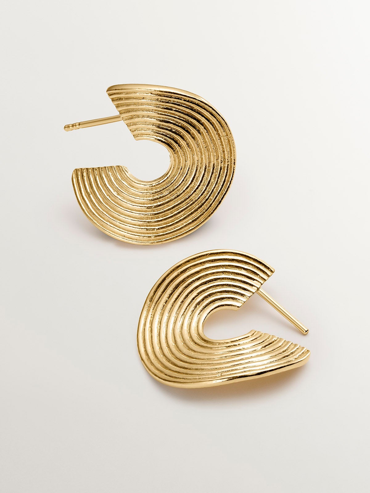 Medium sized hoop earrings made of 925 silver, bathed in 18K yellow gold with texture and irregular shape.