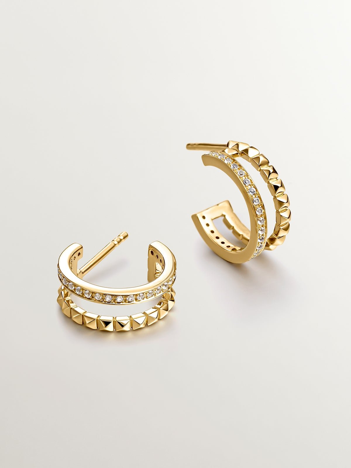 Double hoop earrings made of 925 silver plated in 18K yellow gold with embossing and white topaz.