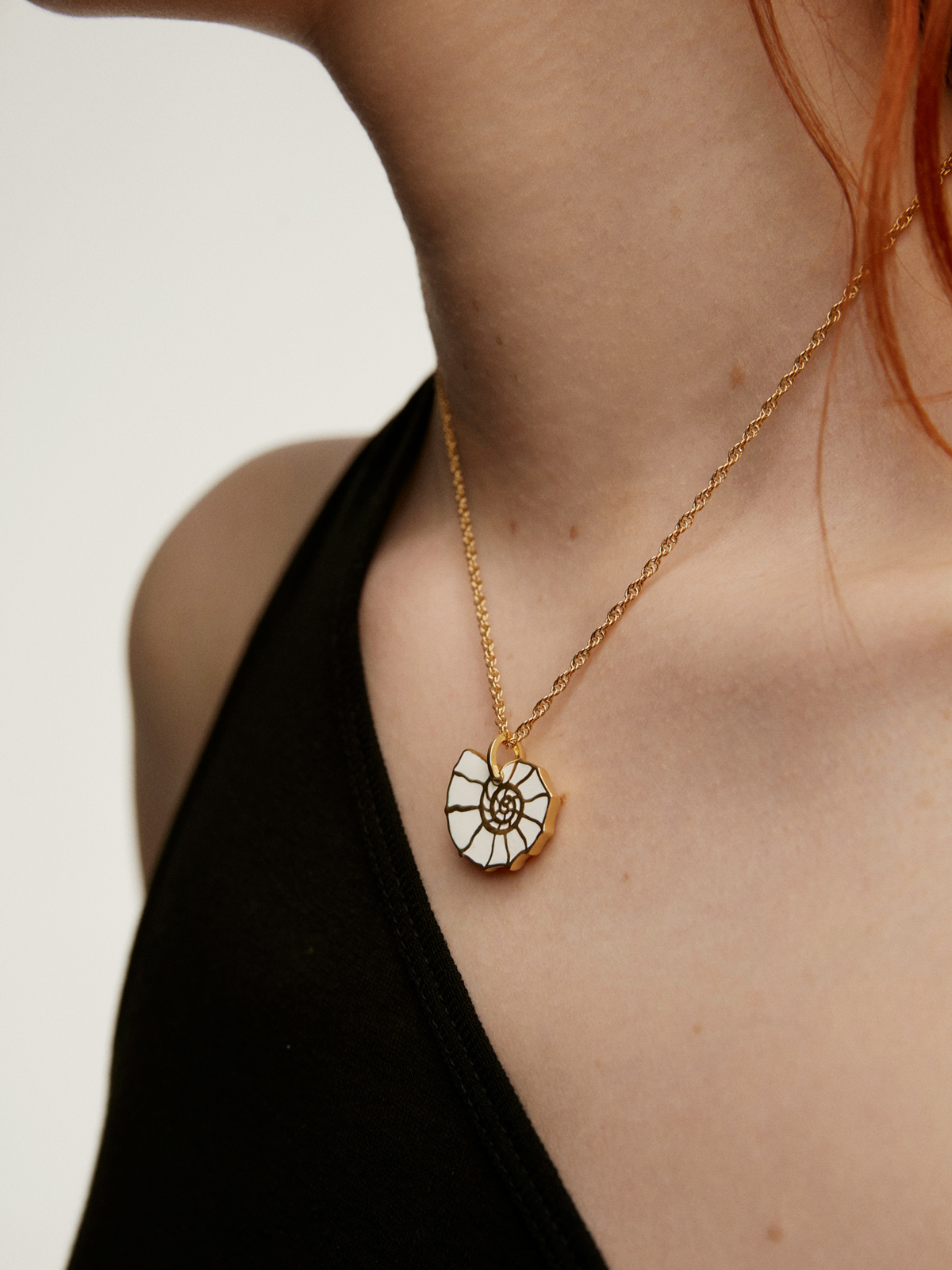 Charm de plata 925 bañada en oro amarillo de 18K con esmaltado blanco y topacios blancos con forma de caracola