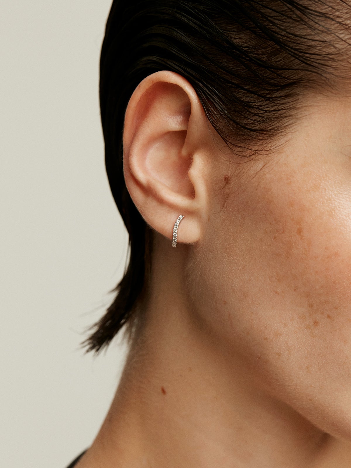 Individual earring of small 18K white gold hoop with diamonds in a wavy shape.