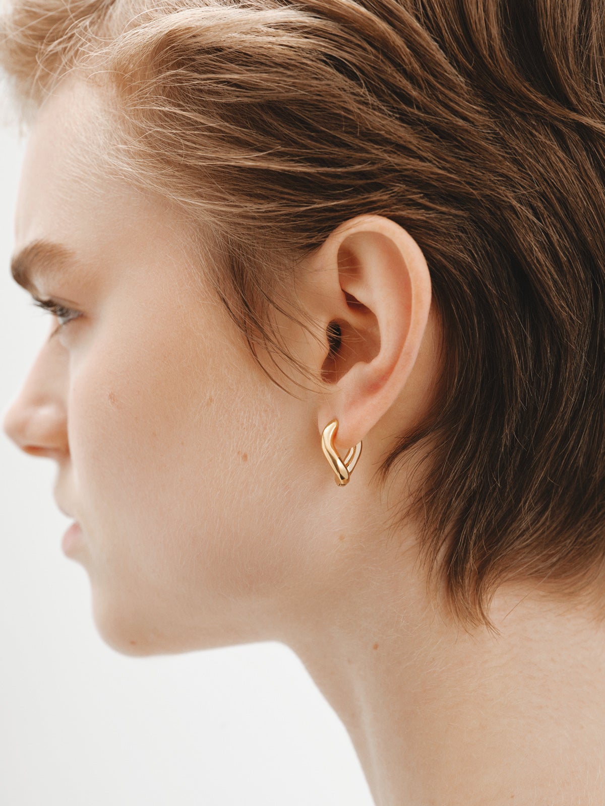 Medium thick 925 silver hoop earrings bathed in 18K yellow gold with a wavy shape.