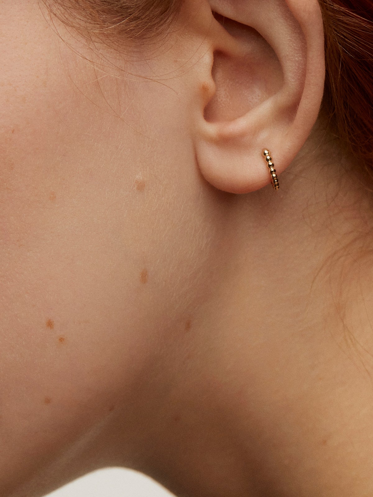 Small individual 9K yellow gold hoop earring with tiny balls.
