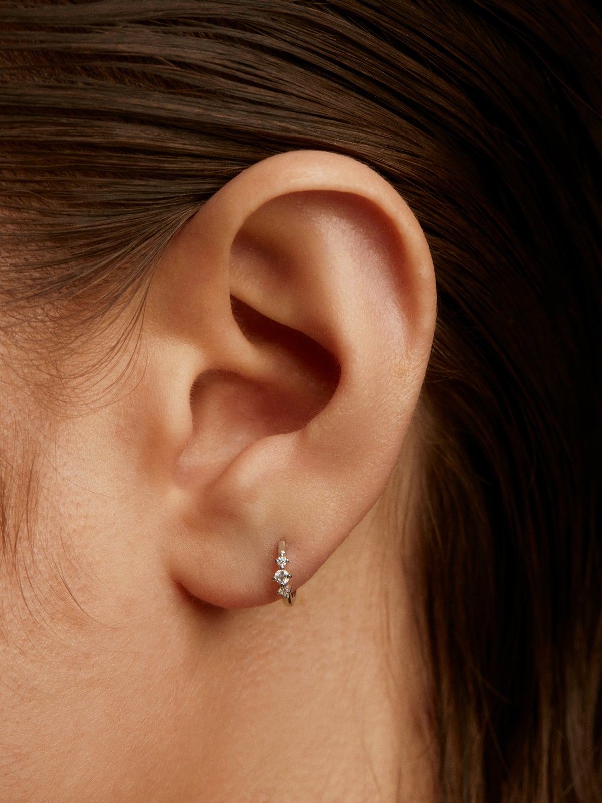 Small individual 18K white gold hoop earring with triple diamond.