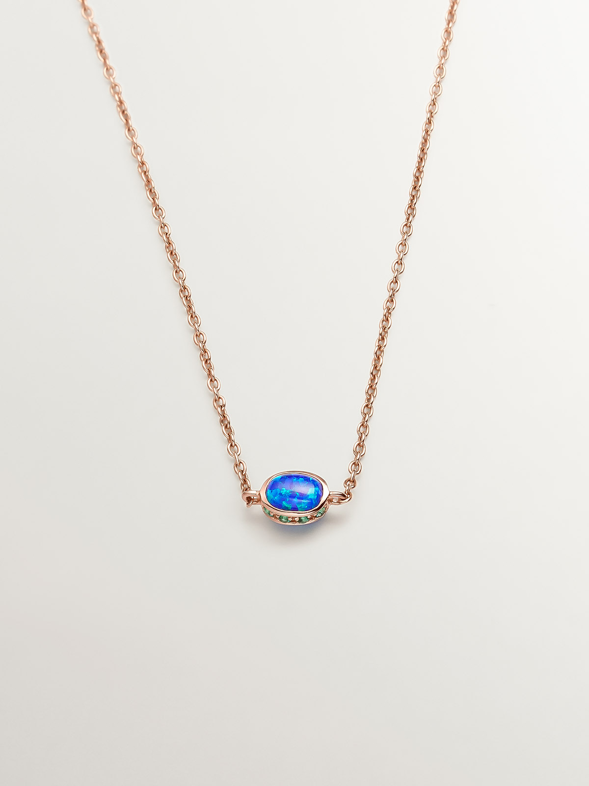 18K rose gold pendant with lab-grown blue opal and emeralds.