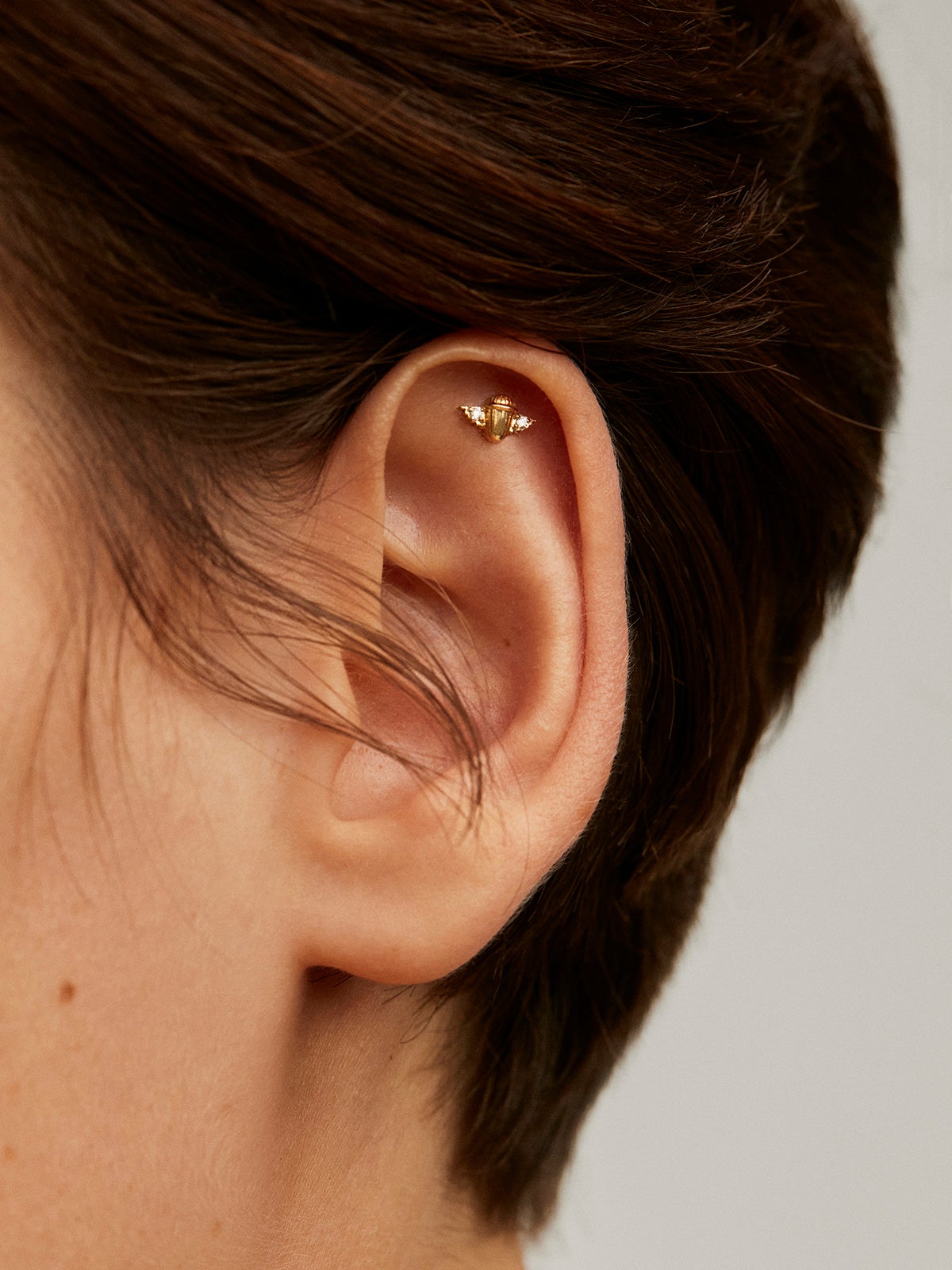 18K yellow gold piercing with diamonds in the shape of a beetle.