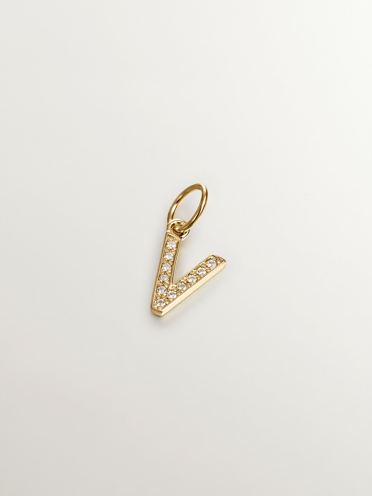 V initial charm made of 925 silver, bathed in 18K yellow gold and adorned with white topaz.