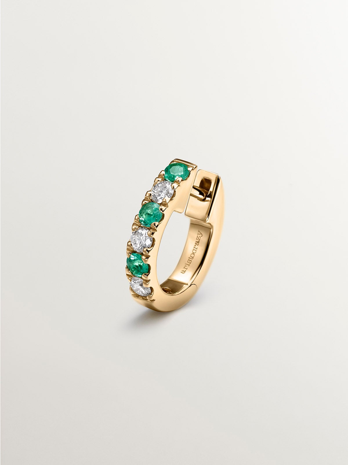 Individual 9K yellow gold hoop earring with emeralds and diamonds.