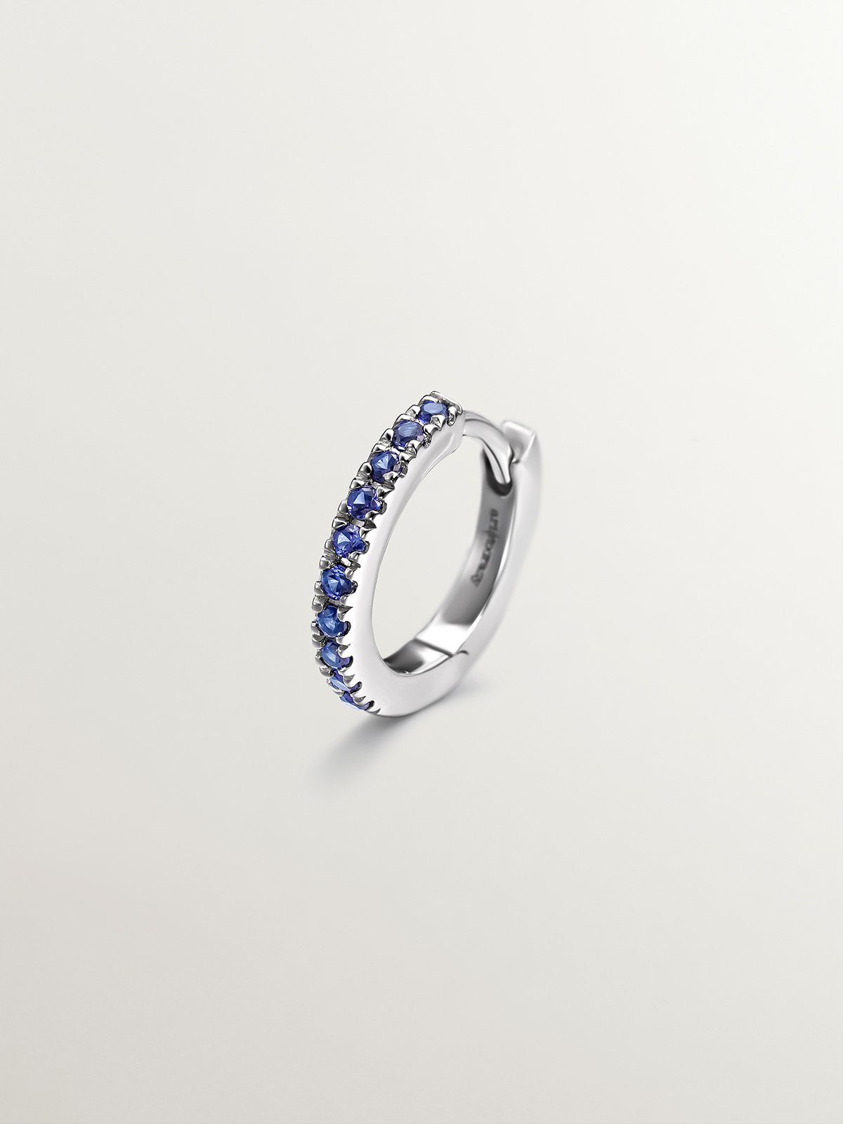 Individual small hoop earring made of 9K white gold with blue sapphires.