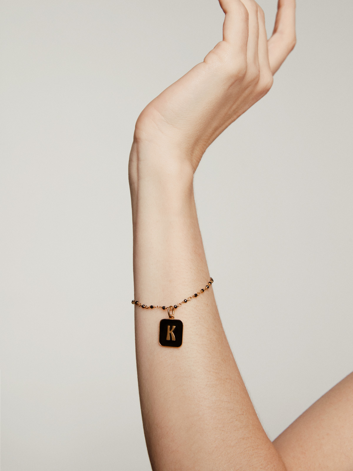 Charm de plata 925 bañada en oro amarillo de 18K con inicial K y esmalte negro con forma cuadrada
