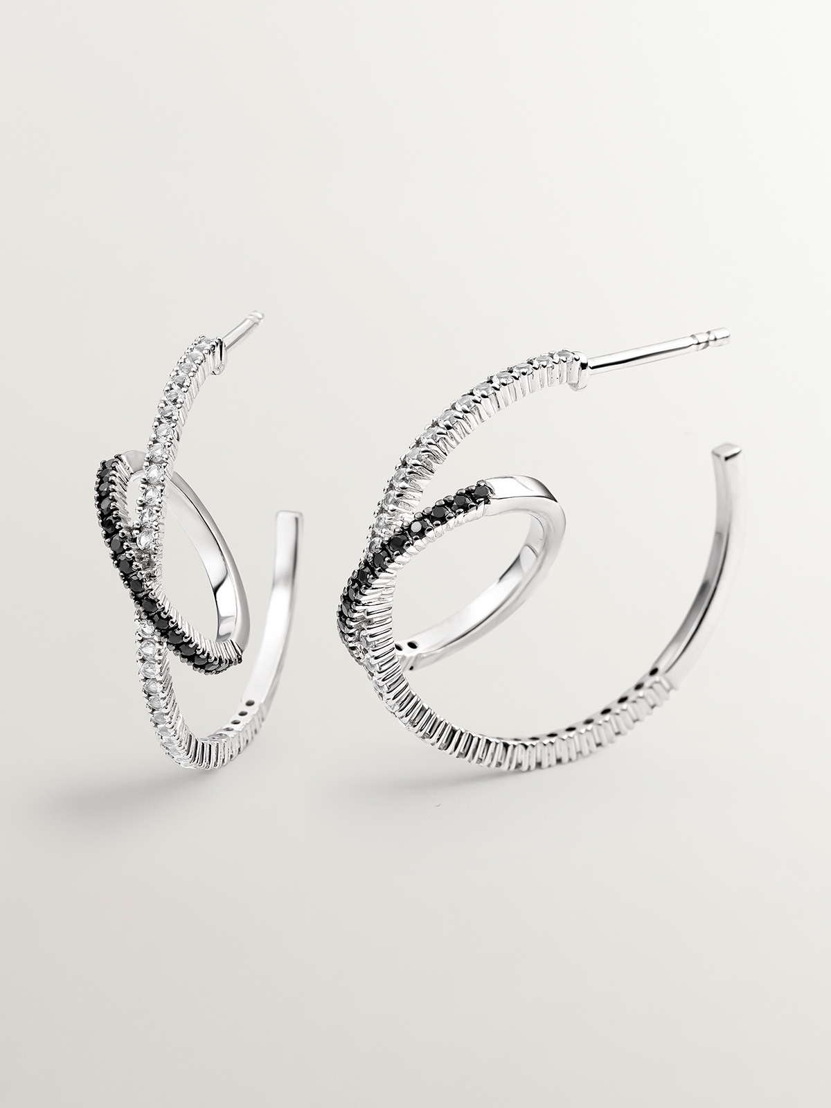 Double hoop earrings made of 925 silver with white topazes and black spinels.