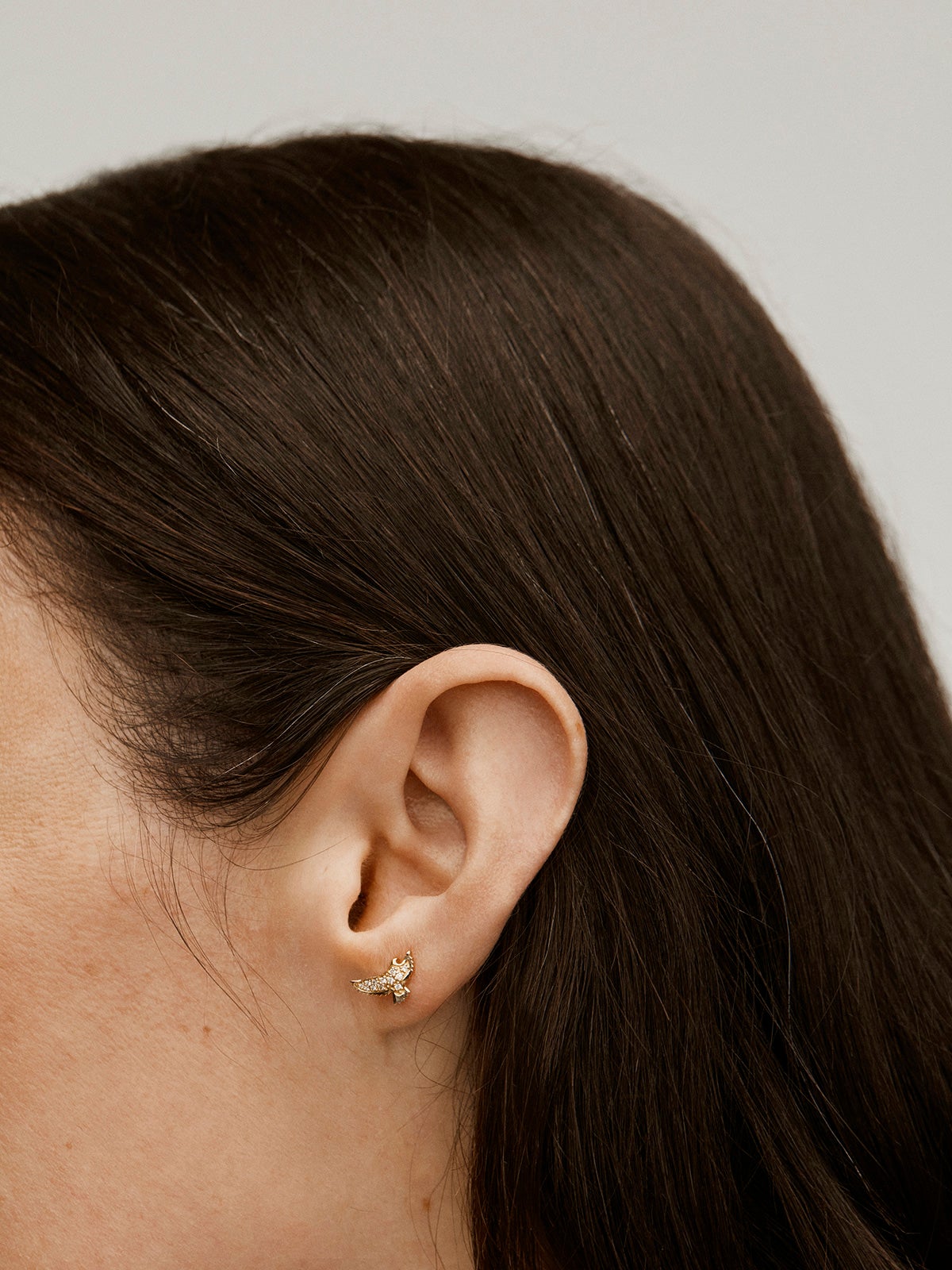 Individual 18K yellow gold earring in the shape of an eagle with diamonds.