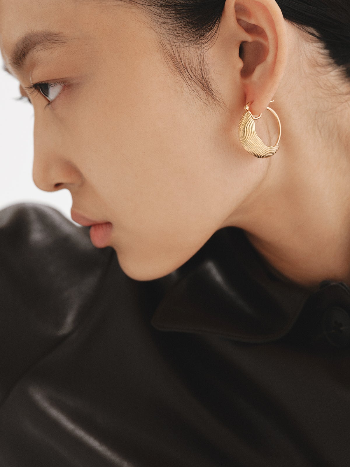 Medium hoop earrings made of 925 silver coated in 18K yellow gold with relief and irregular shape.