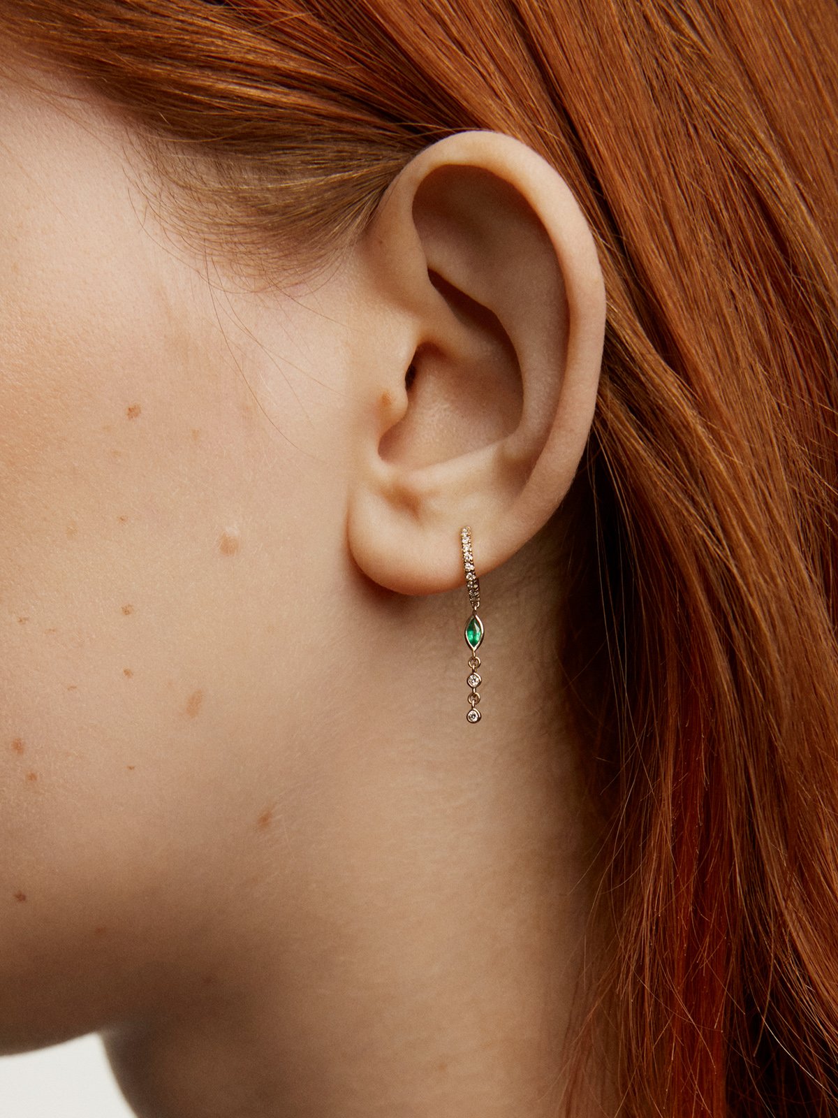 Individual small hoop earring made of 9K yellow gold with a diamond chain and emerald.