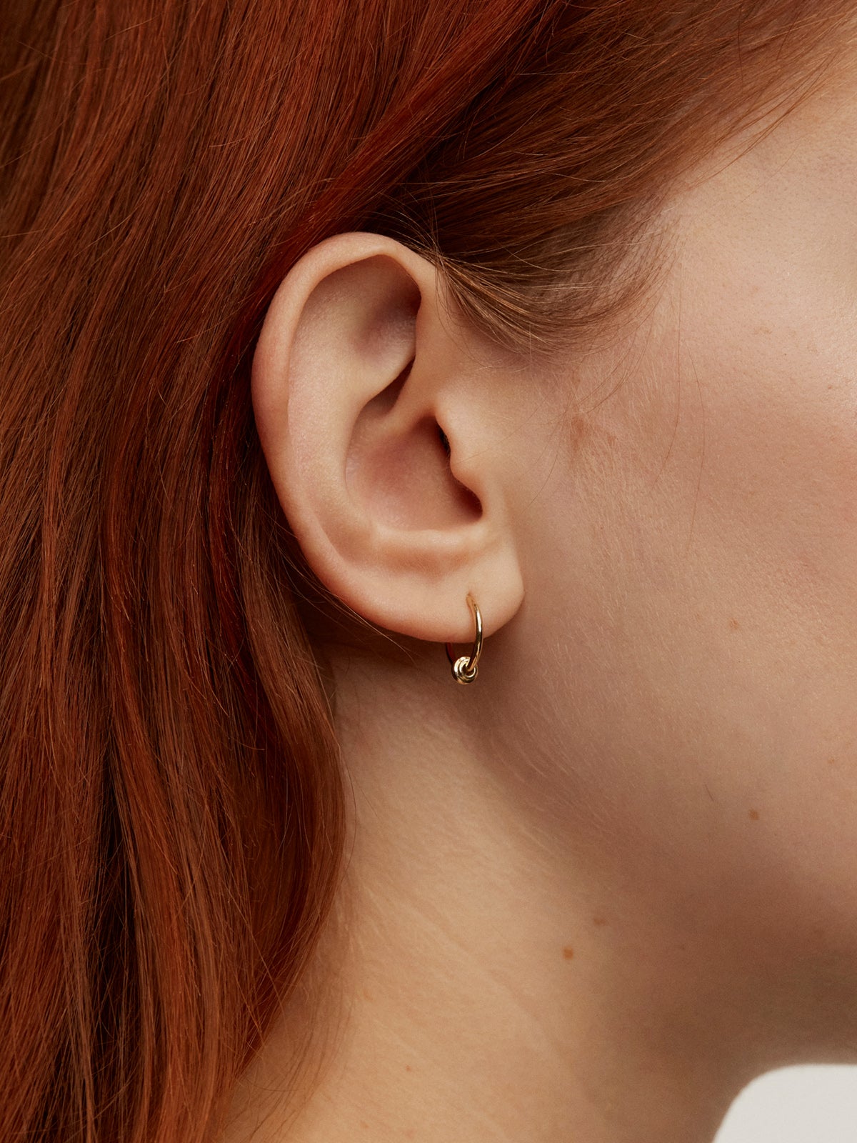 Individual 9K yellow gold hoop earring with a small ball.