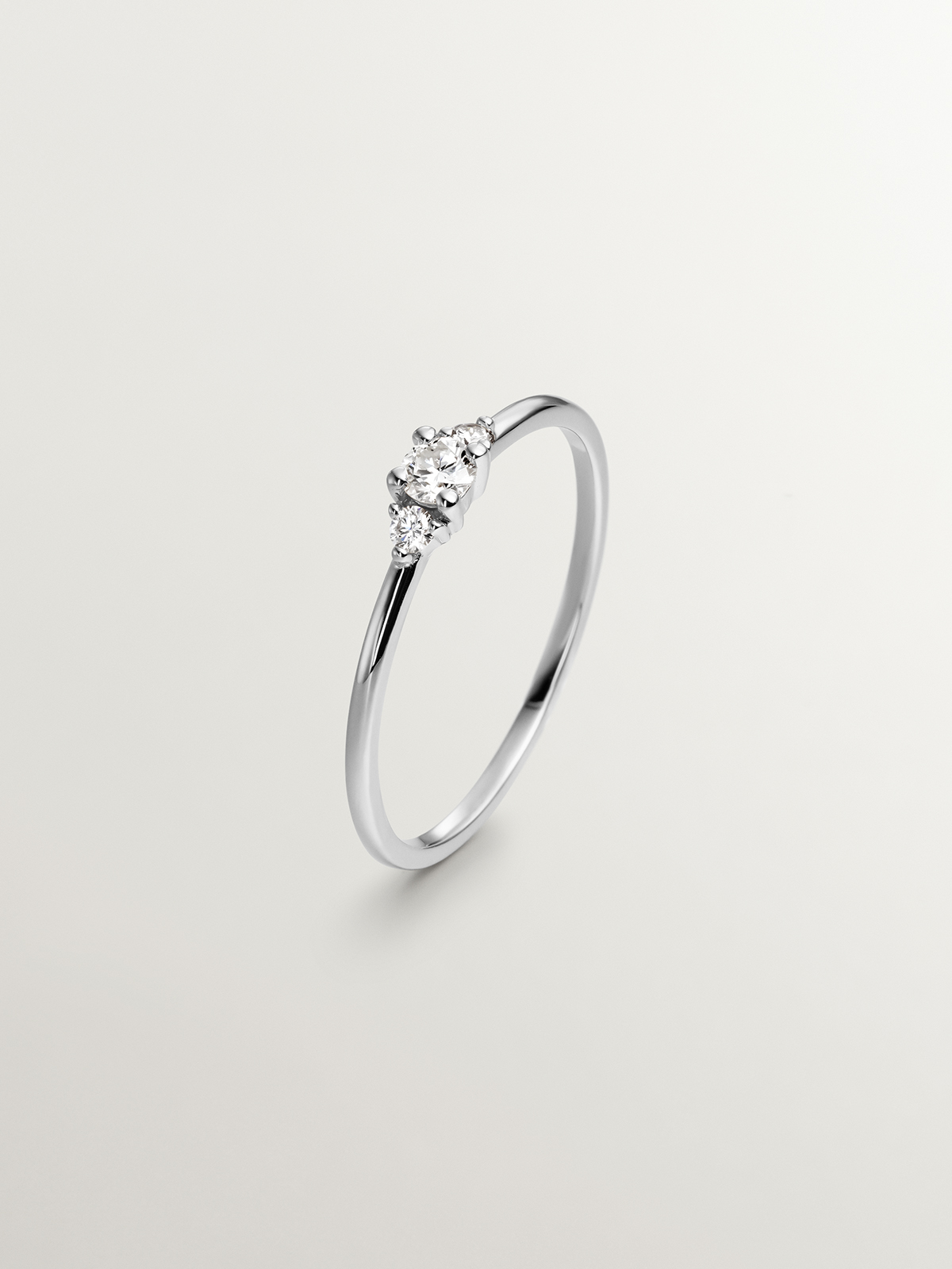 Anillo tresillo de oro blanco de 18K con diamante central de 0,10cts y diamantes