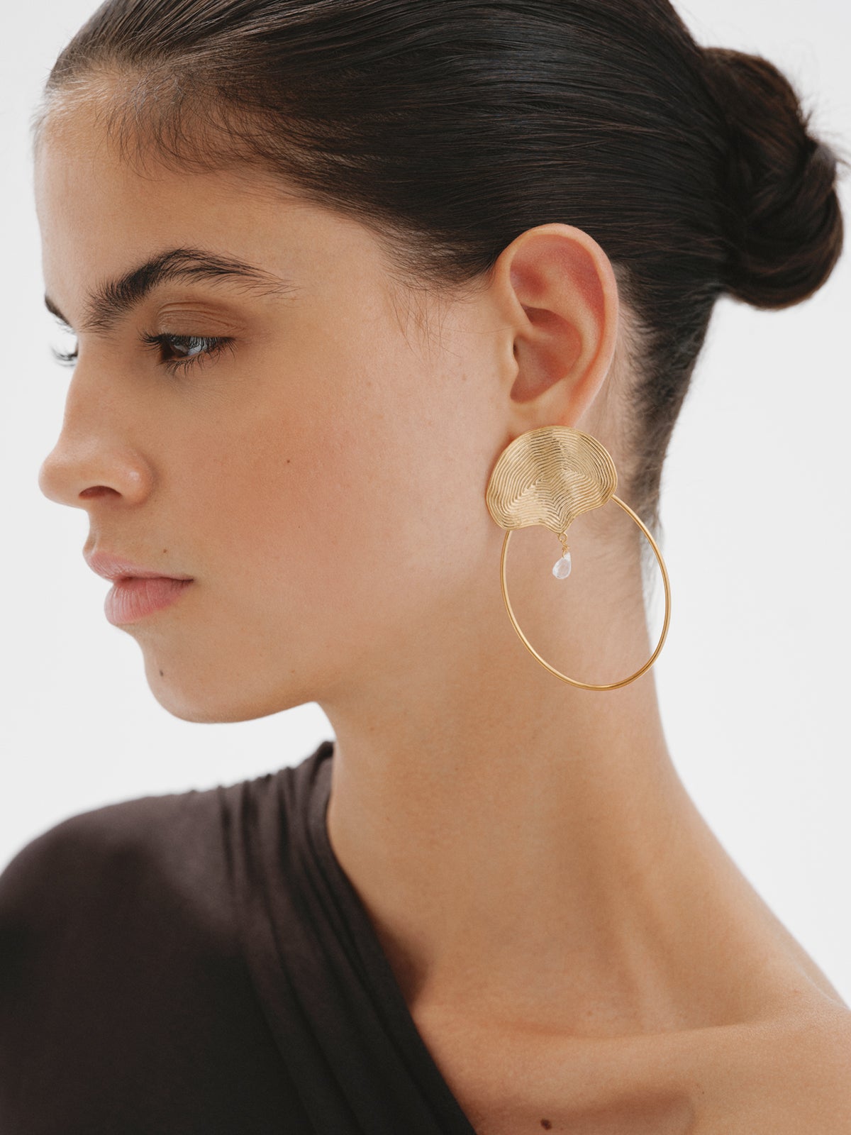 Boucles d'oreilles créoles en argent 925 plaqué or jaune 18K avec relief et topaze blanche.