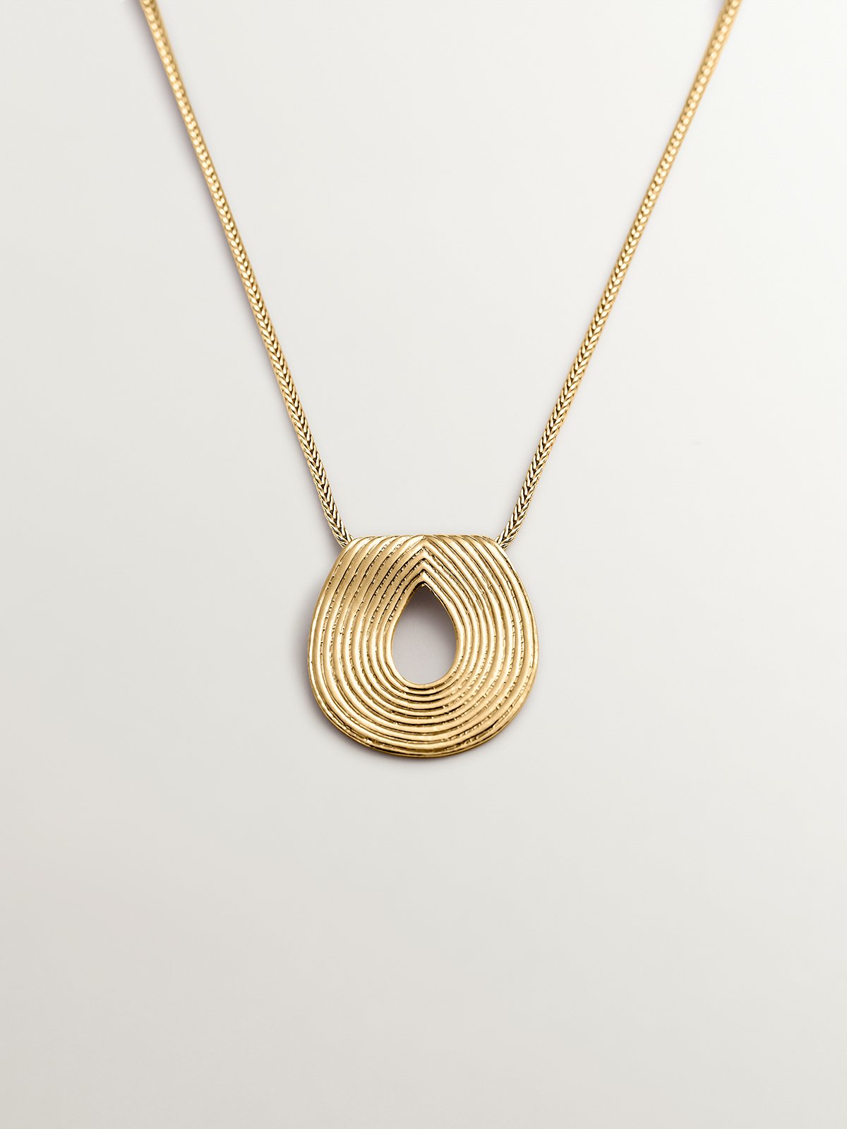 Oval pendant made of 925 silver bathed in 18K yellow gold with relief.