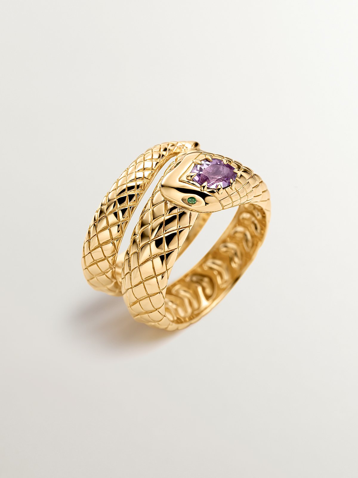 Wide 925 silver ring bathed in 18K yellow gold with a snake shape, purple amethyst and green tsavorites.
