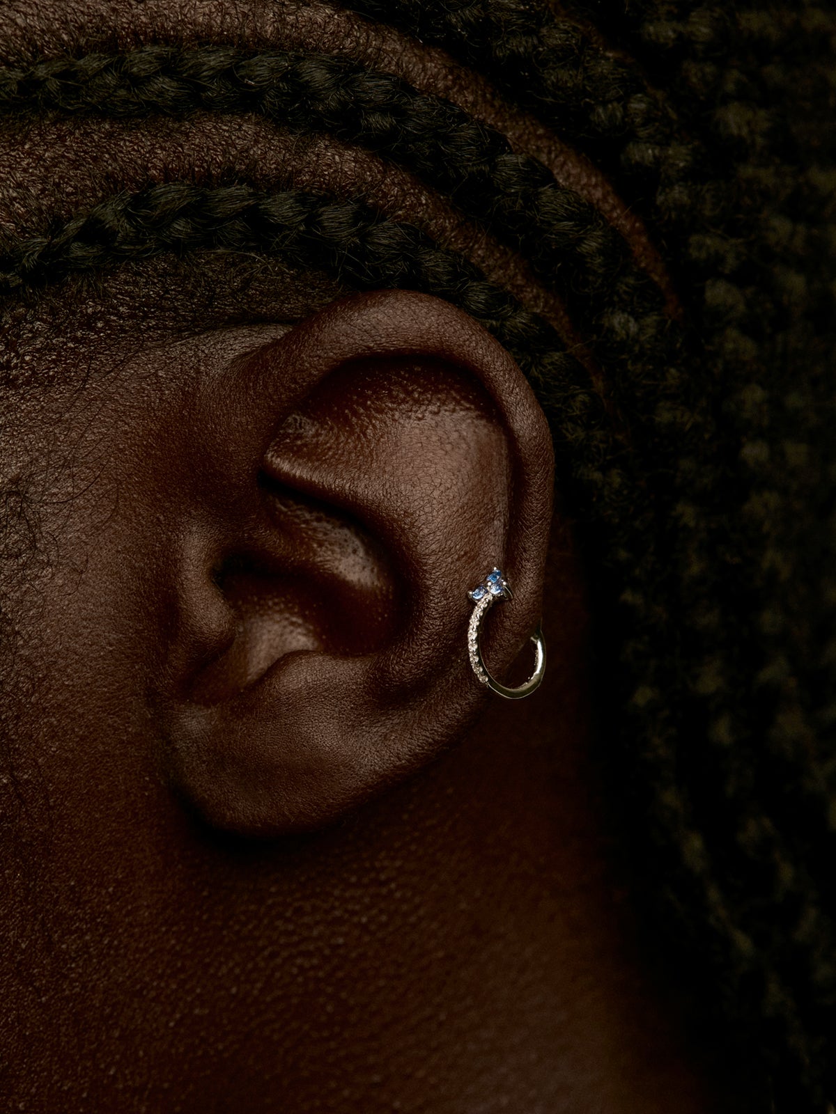 Individual small hoop earring made of 9K white gold with a blue sapphire and diamond clover.